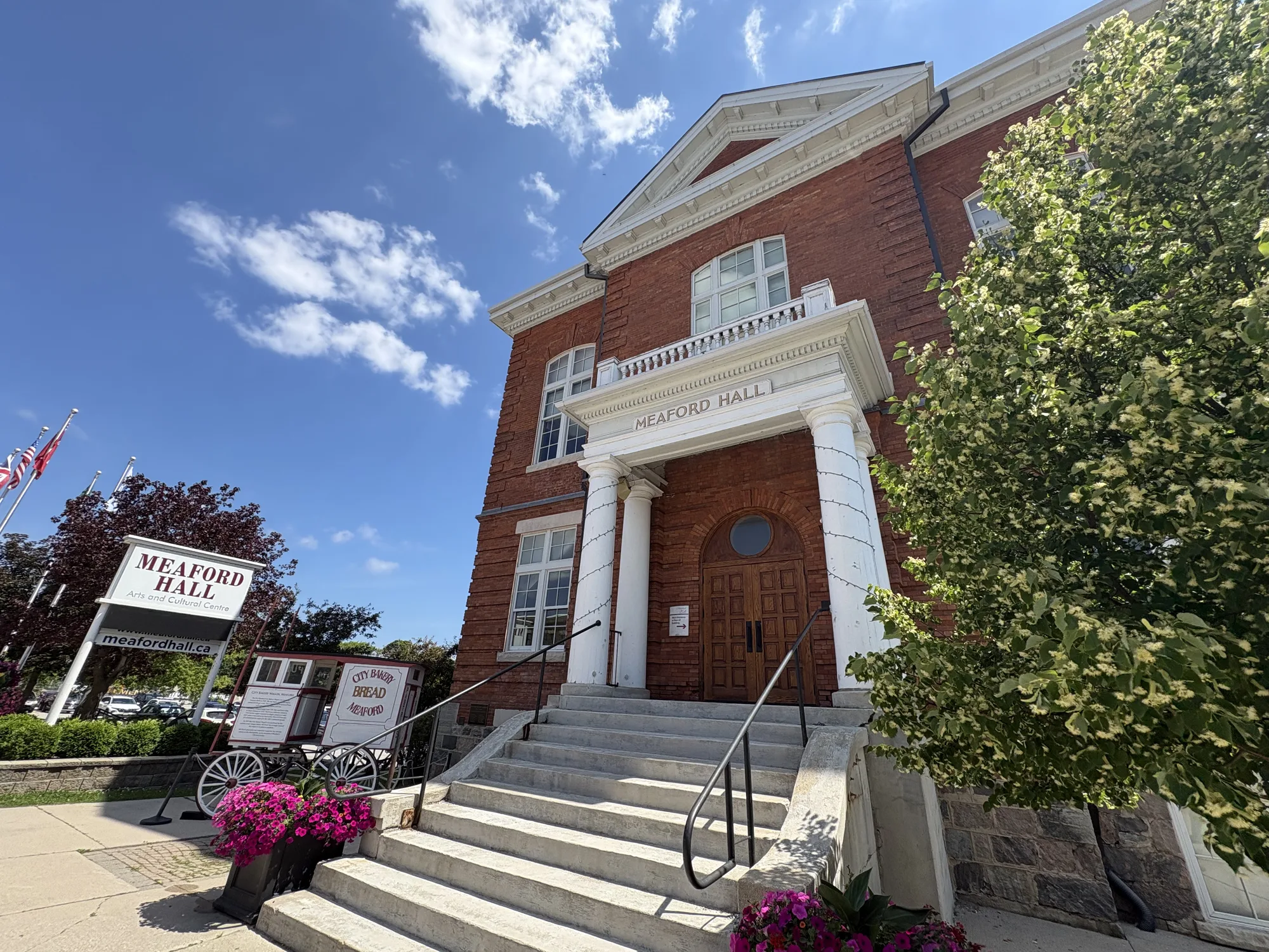 Historic red-brick Meaford Hall with flower baskets and a Canadian flag on the main street of Meaford