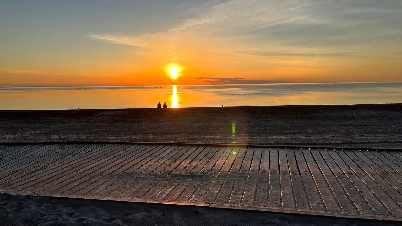 An orange sunset over the boardwalk and sand at Wasaga Beach.