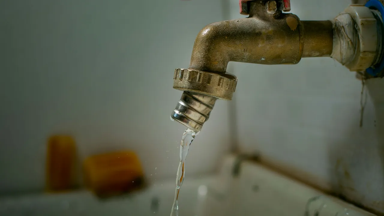 A brass tap dripping water into a sink.