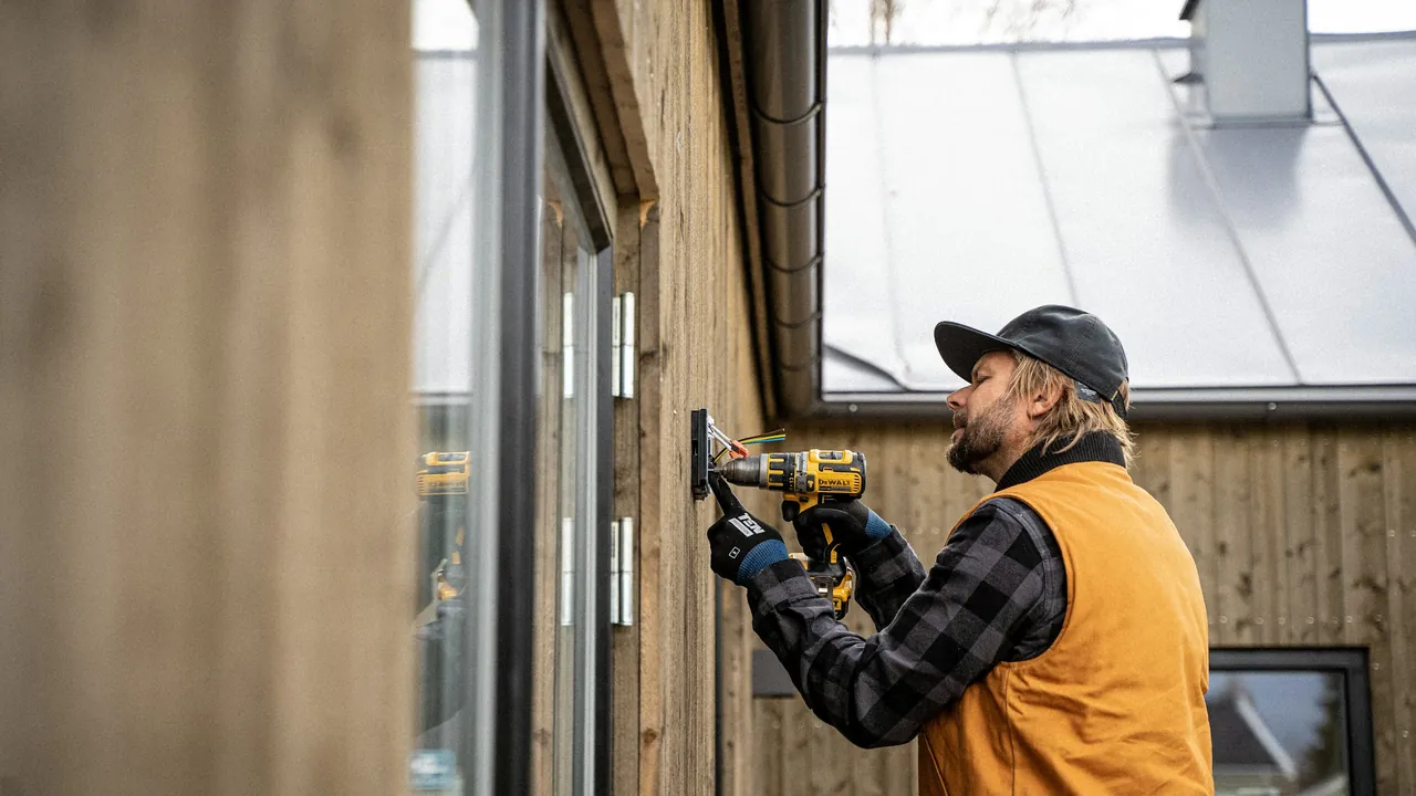 A tradesman with a cordless drill fitting out a timber house.