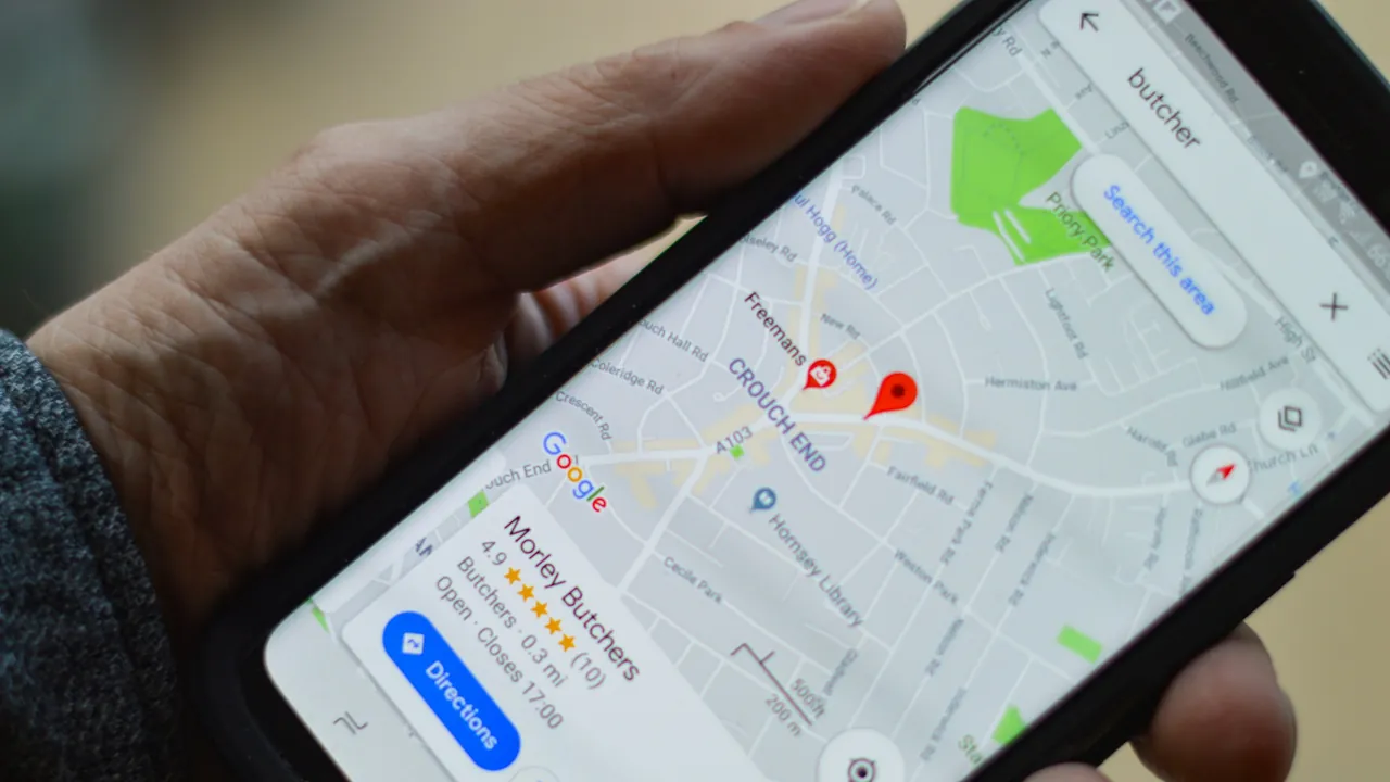 A hand holding a phone with Google Maps showing nearby businesses and their star ratings.