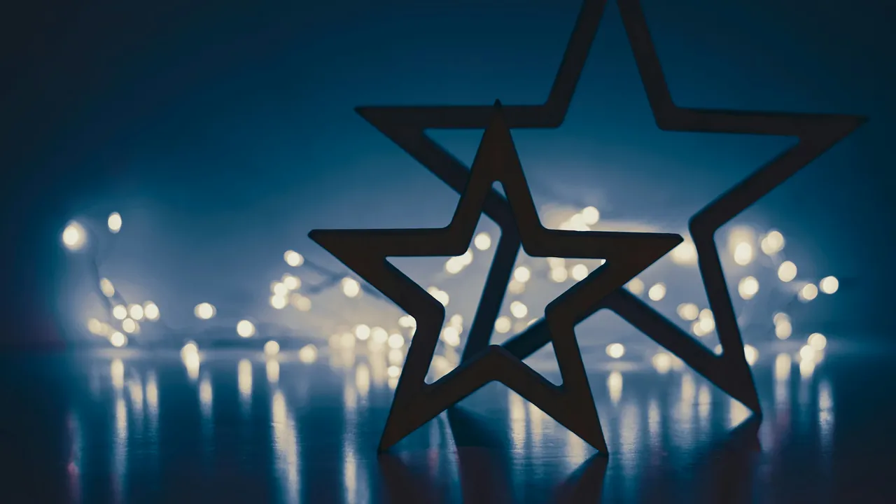 Two outlined stars against a dark blue background of blurred lights.