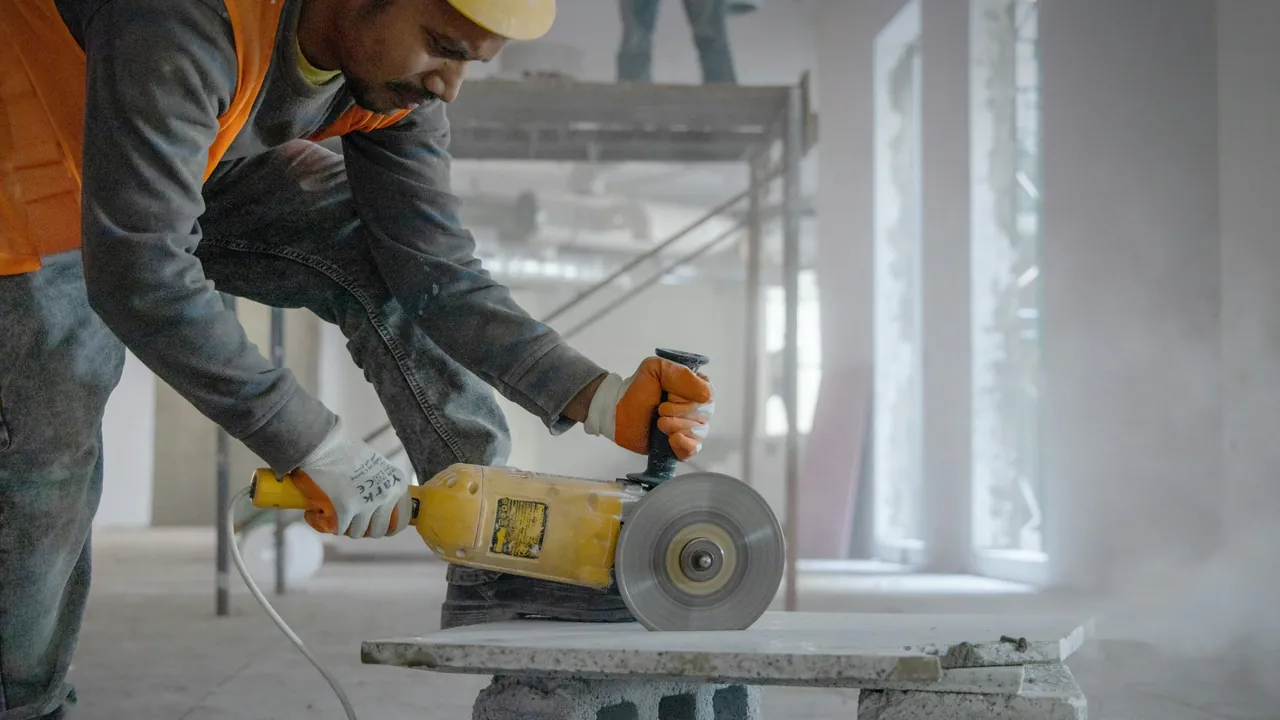 A tradesman cutting stone with an angle grinder on a job site.