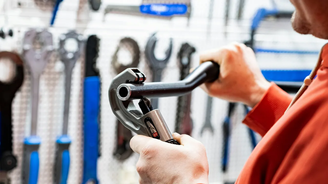 A tradesman taking a pipe tool from a neatly organized pegboard of tools.